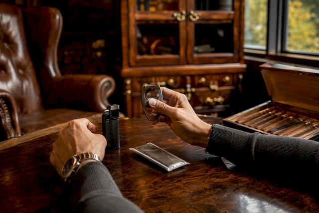 Hands arranging cigar accessories on wood table