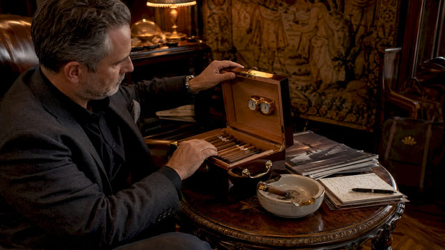 Man examining luxury wooden humidor at desk